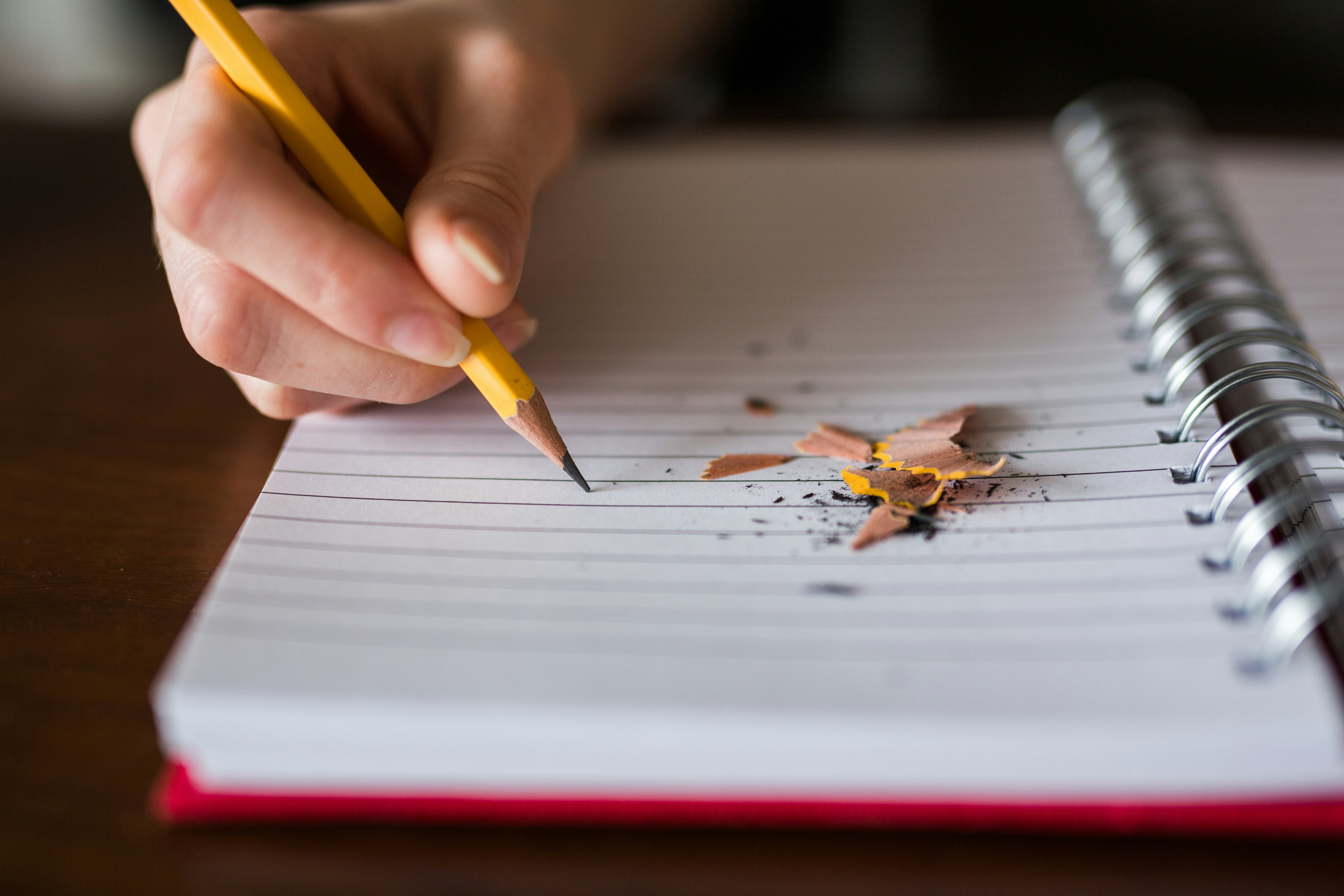 person writing on paper with a pencil