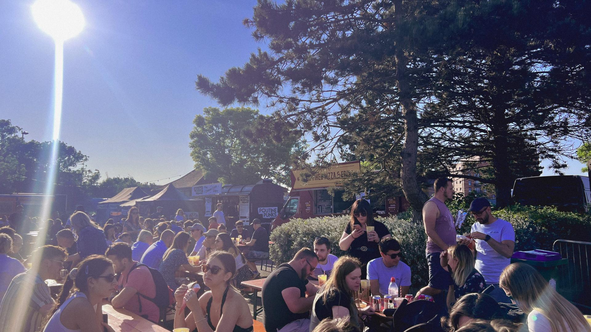 people sat on tables and benches socialising enjoying the sun