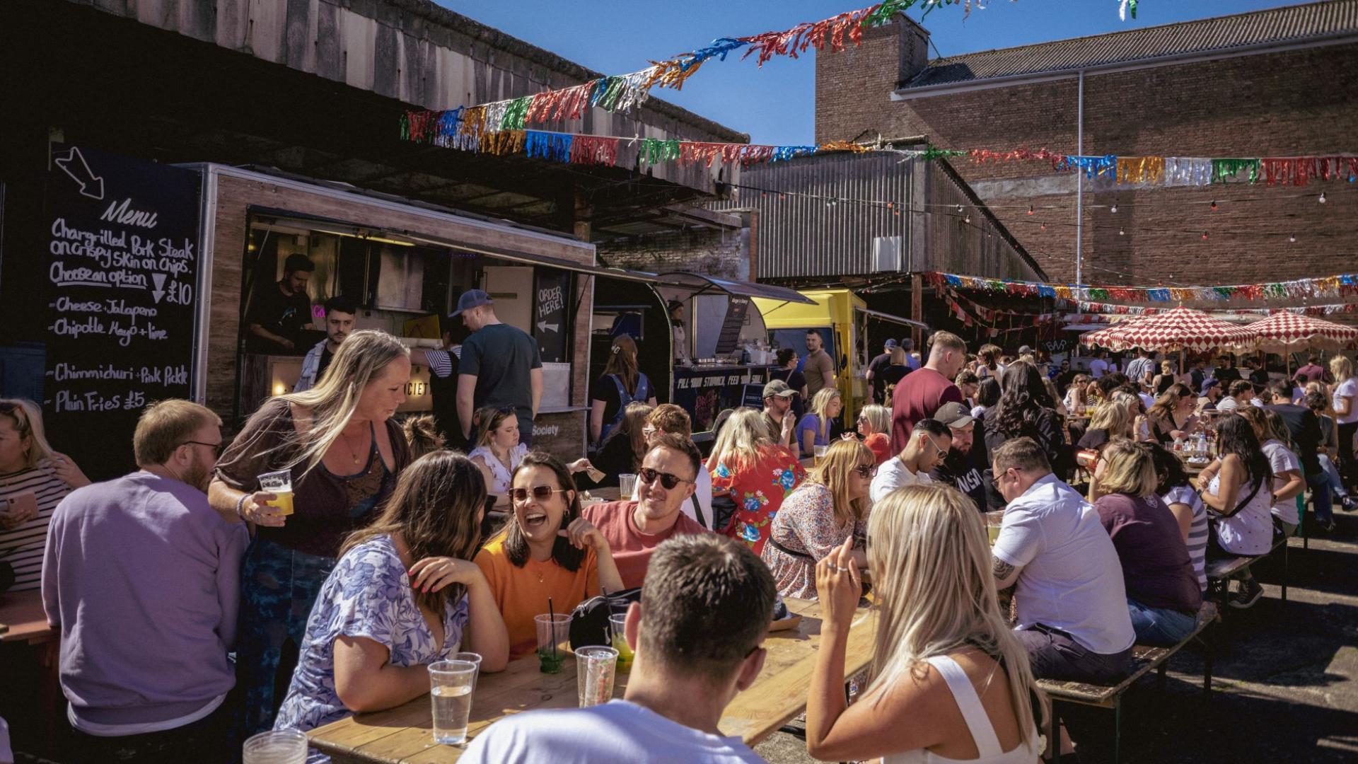 People socialising in a area surrounded by food stalls