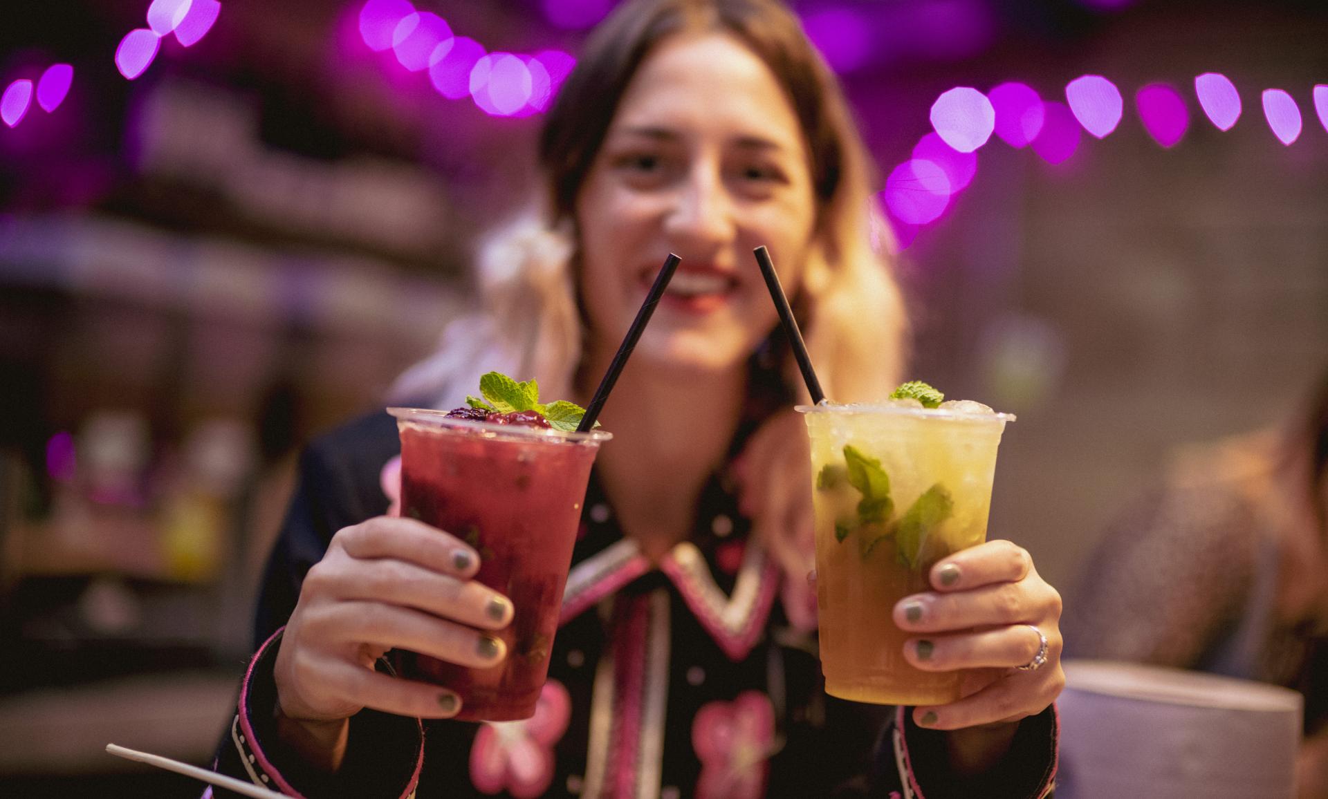 a girl holding 2 drinks